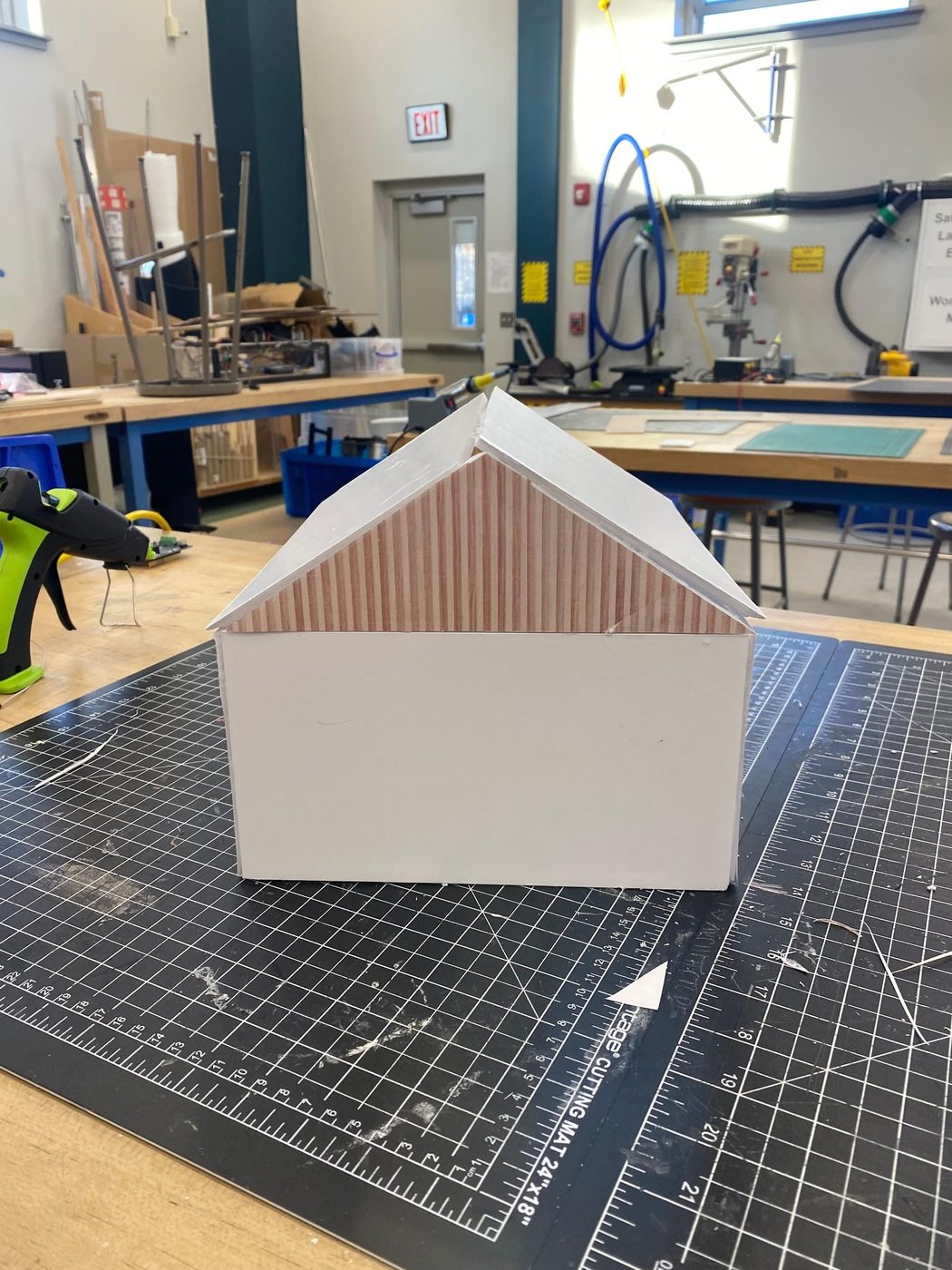 The gable end of a foam board tiny house model covered in a color-printed vertical wood siding pattern