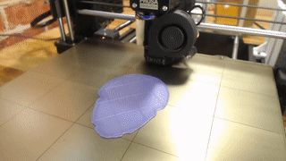 A purple print building up layer by layer on the printer bed